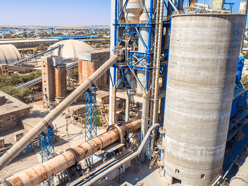 Cement plant exterior with bulk cement in foreground and silos behind: Mole&middot;Master&reg; on-site cleaning