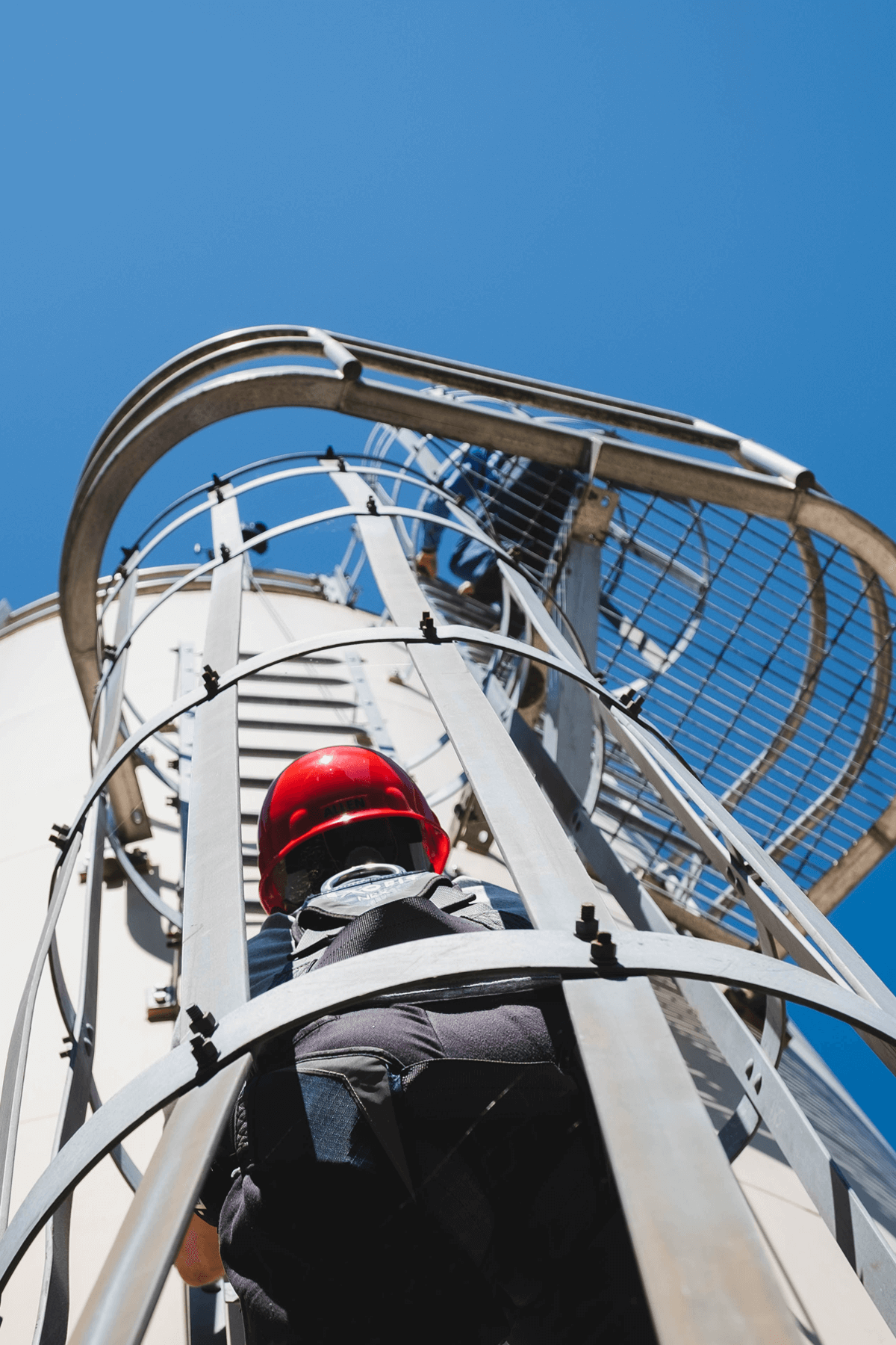 Worker climbing ladder on silo exterior